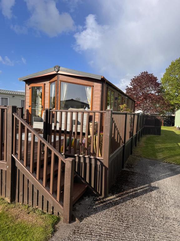 a tiny house sitting behind a wooden fence at 10 the green lilliardsedge carvan park harritsfield jedbrugh td8 6tz in Harrietsfield