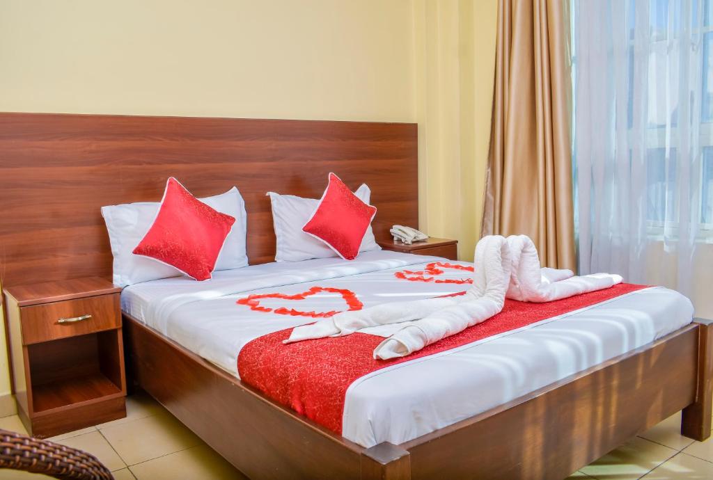 a bedroom with a bed with red and white pillows at Delfirm Hotel in Nairobi