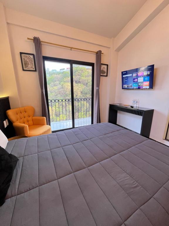a bedroom with a large bed and a large window at HOTEL BOUTIQUE ÁRBOL De LA VIDA in Taxco de Alarcón