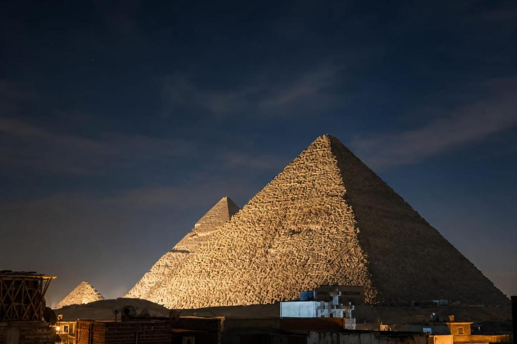 a view of the pyramid of giza at night at Sol Pyramids Rooftop View Giza in Cairo