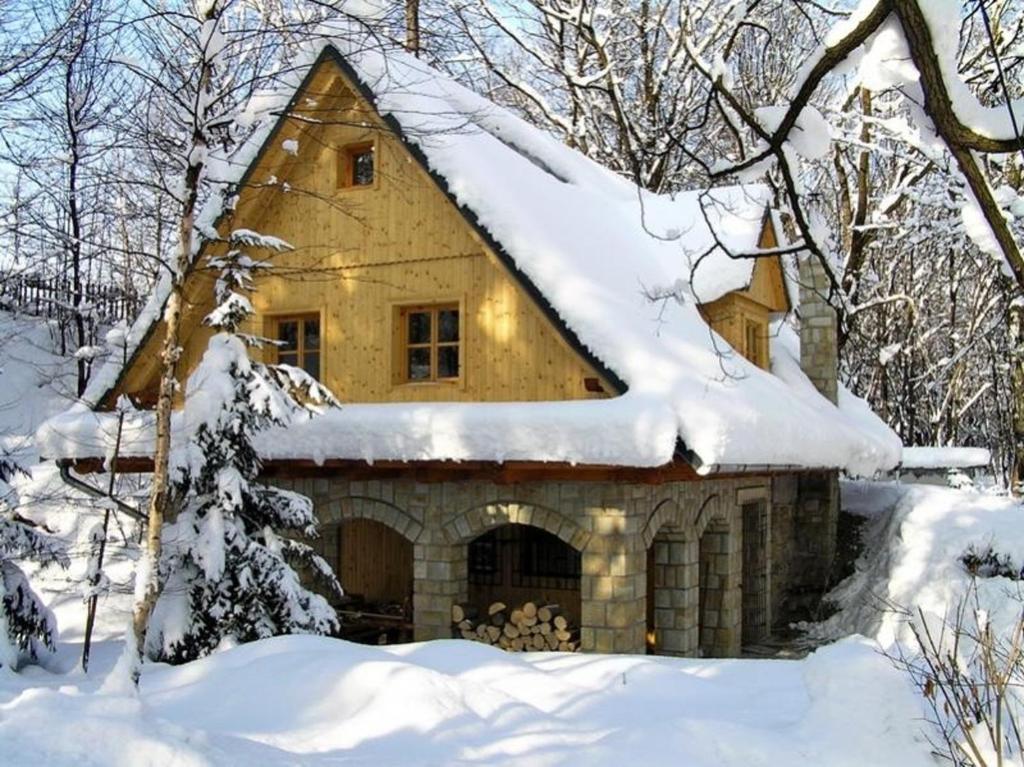 a house with a snow covered roof in the woods at Apartmán Belko in Hrádek