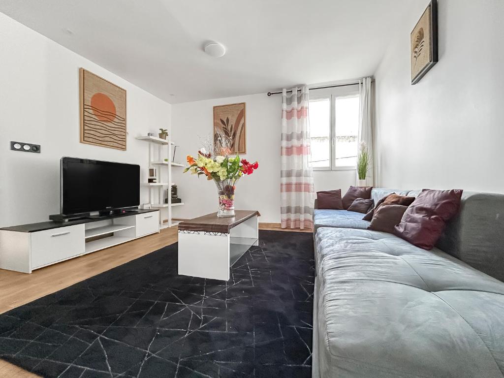 a living room with a couch and a tv at Appartement 2 chambres - Arrivée autonome - Wi-Fi Fibre in Bruay-la-Buissiere