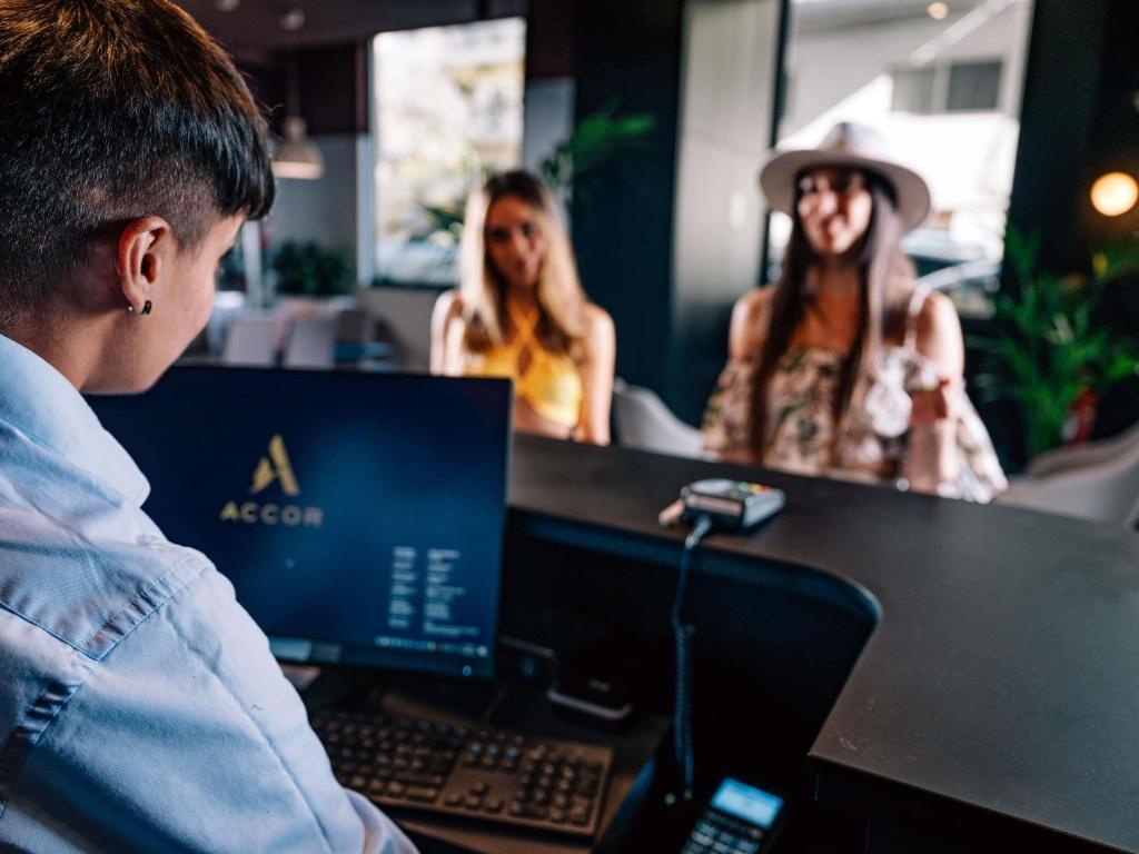 a man sitting at a desk with a computer at Aparthotel Adagio Malta Central in Msida