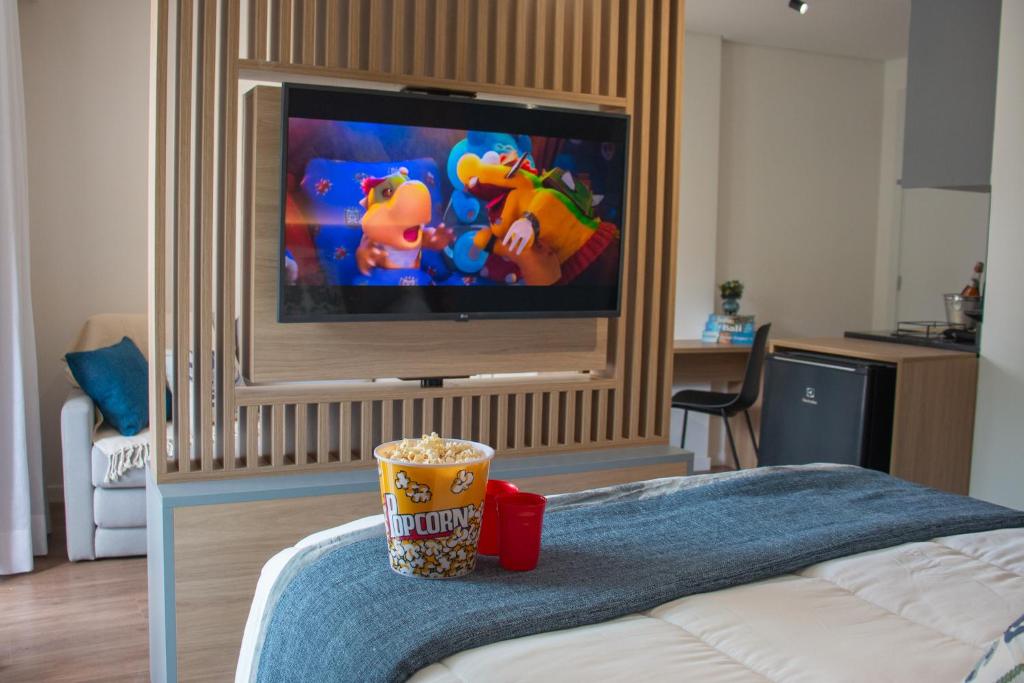 a room with a television and a cup on a bed at Loft completo no Centro de Itaipava in Araras Petropolis
