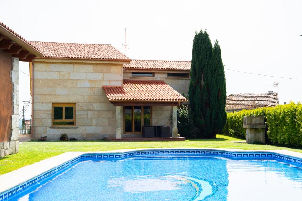 a swimming pool in front of a house at Welcome Villa O Sidrón in Alba
