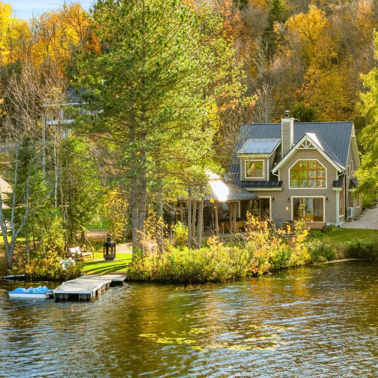 a house on a river with a boat in the water at Waterfront with VIEW and SPA in Saint-Raymond