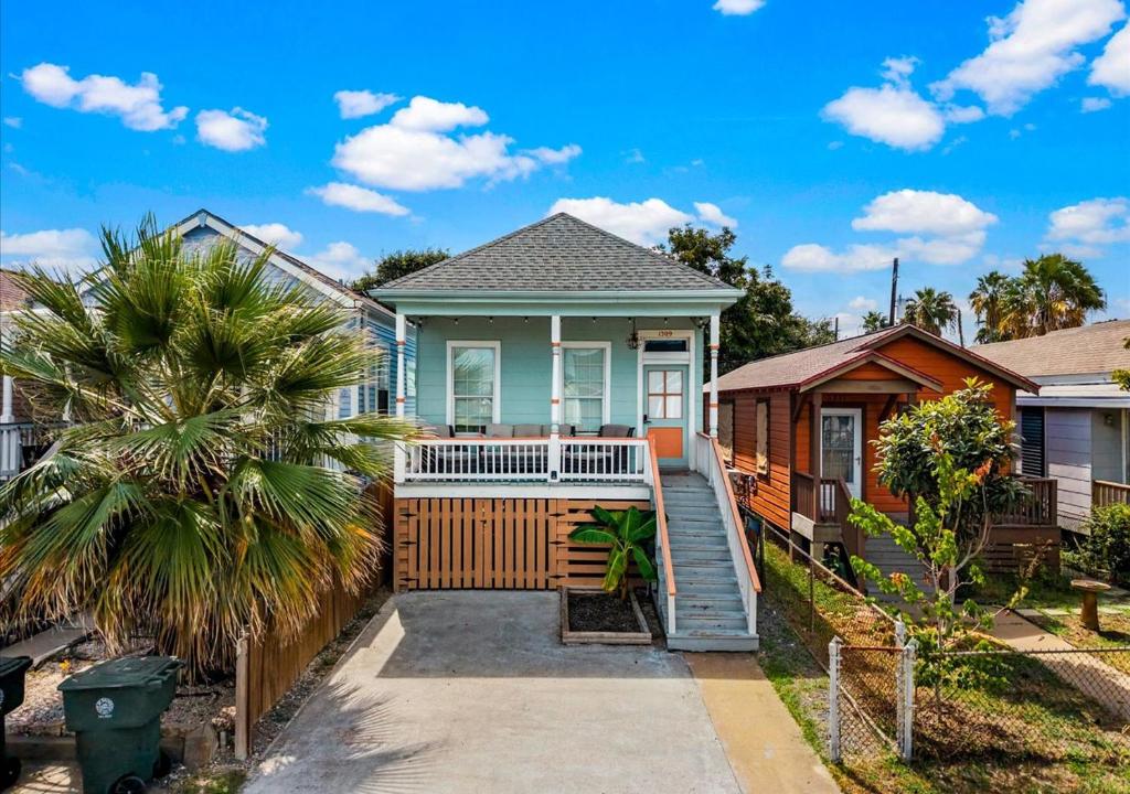 a house with a porch and a palm tree at Blue Heron Cottage in Galveston