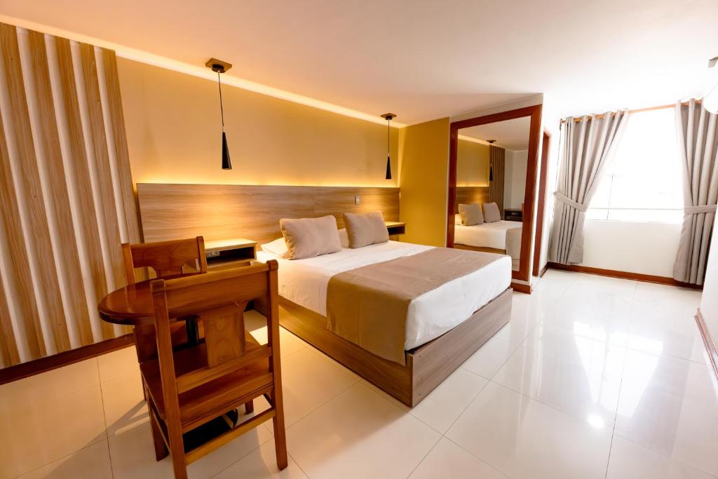 a hotel room with a bed and a table and a desk at Hostal Los Cactus in Lima