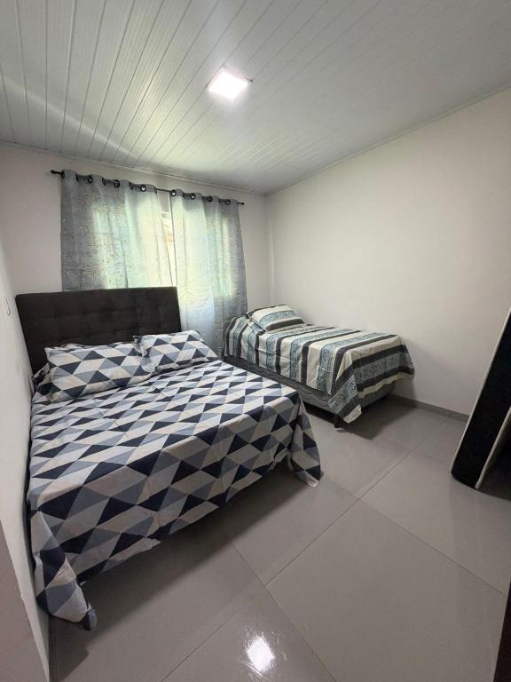 a bedroom with two beds and a window at Casa queen in Campo Grande