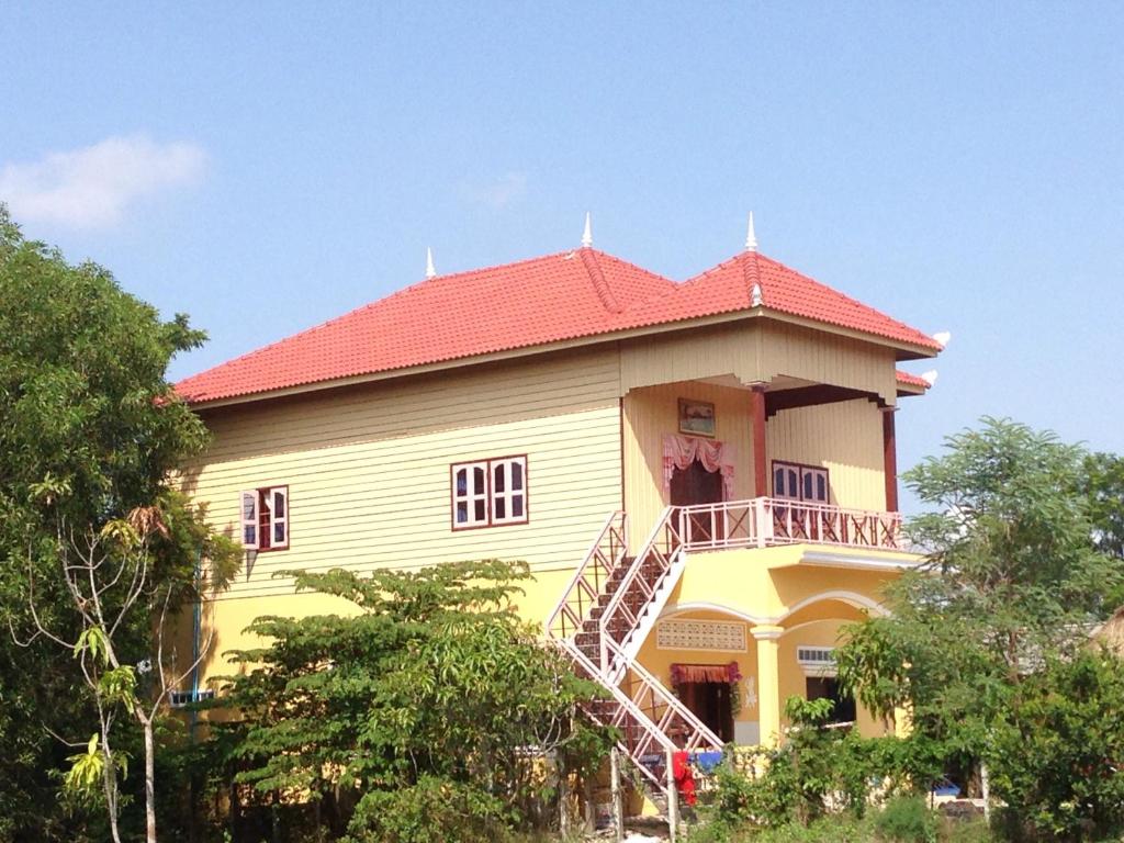 uma casa amarela com um telhado vermelho e uma escada em Bunyong Homestay em Siem Reap