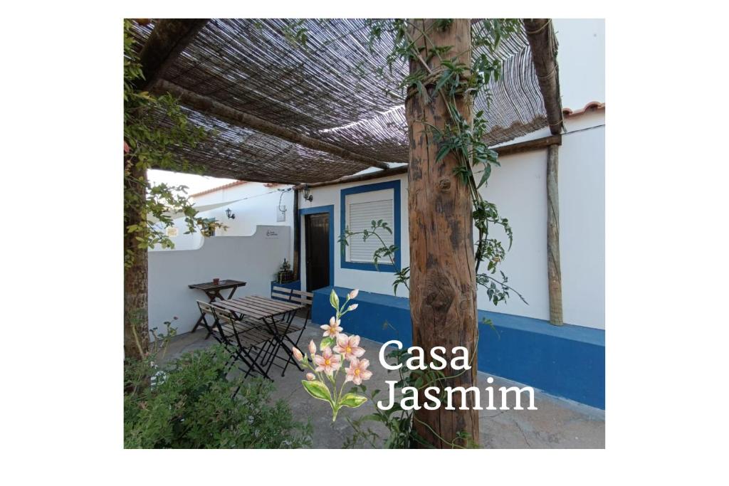 a porch of a house with a table and a tree at Casas do Montinho in Melides