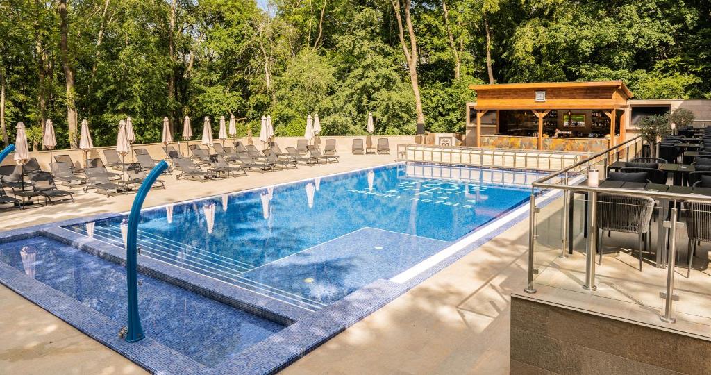 a large swimming pool with chairs at The Hotel Unforgettable - Hotel Tiliana by Homoky Hotels & Spa in Budapest