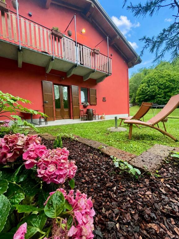 a red house with a balcony and pink flowers at Casa Iris in Omegna