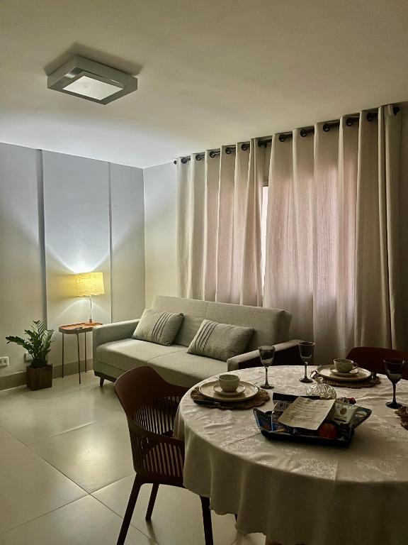 a living room with a couch and a table at Flat Aconchego no Setor Oeste a 50m do Lago das Rosas, apto novo in Goiânia