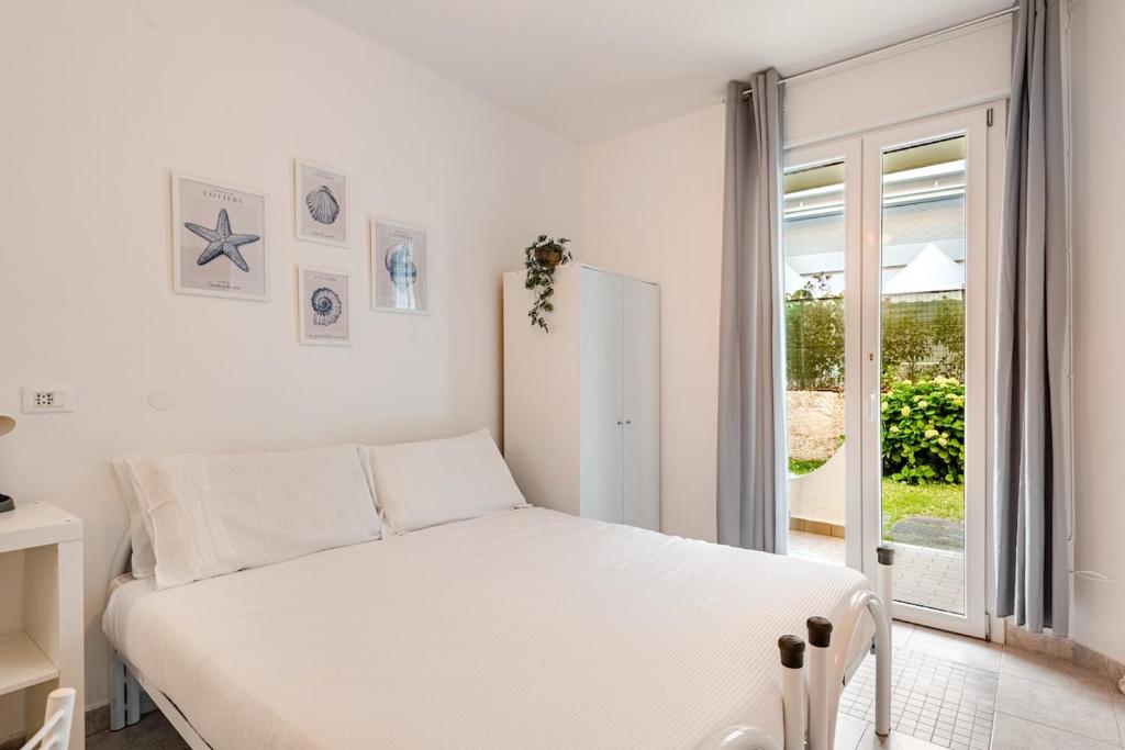 a white bedroom with a white bed and a window at Beachfront Studio Free Parking-Pool 50m from Sea in Chioggia