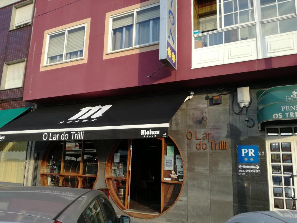 a restaurant with a black awning in front of a building at Pensión Los Trillizos in Boiro
