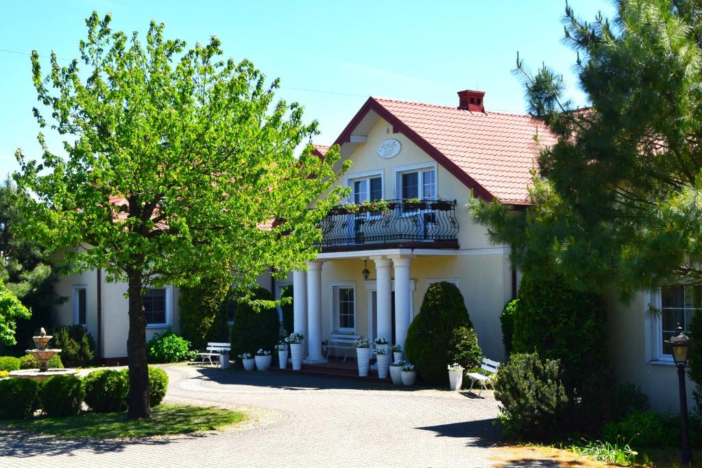 a white house with a balcony and trees at Dwór Zielone Wzgórza in Bukowno