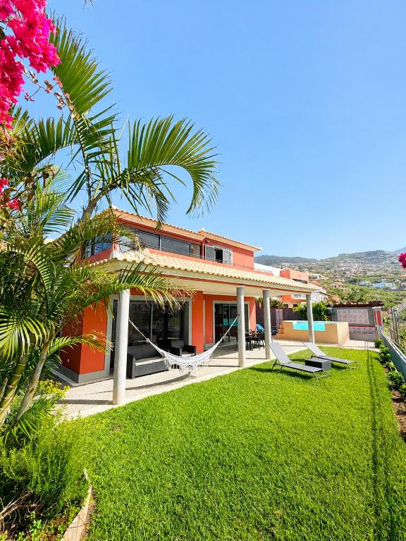 an orange house with a lawn in front of it at Casa do Piquinho in Ponta do Sol
