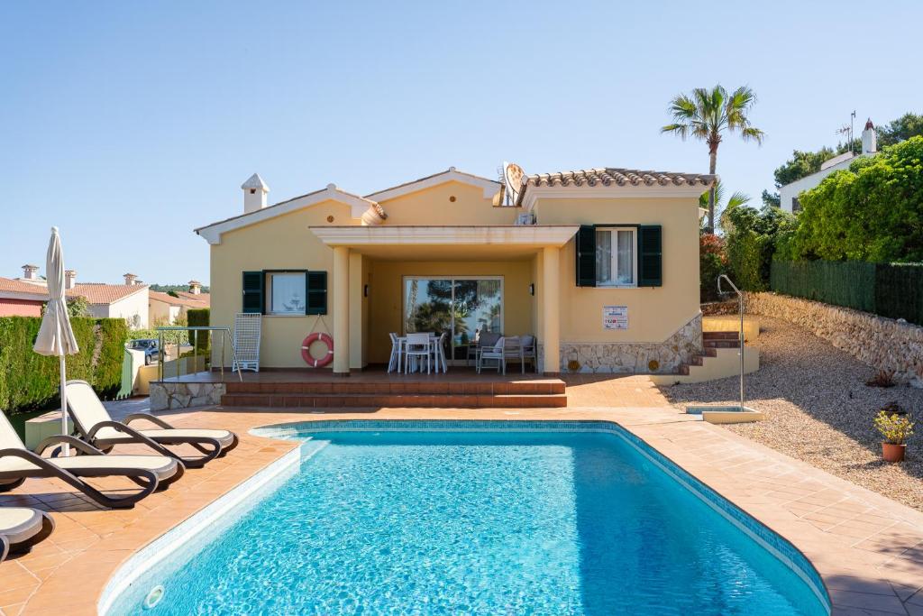 a villa with a swimming pool in front of a house at V155 Villa Llebeig in Son Bou