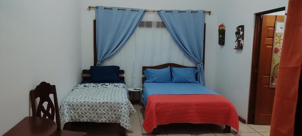 two beds in a room with blue curtains at las cabinas del sueño in Nicoya