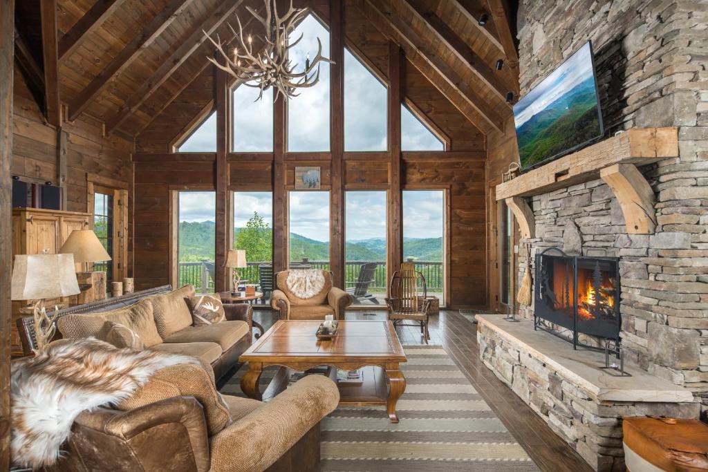 a living room with a fireplace and a stone wall at Cucumber Tree Lodge in Banner Elk