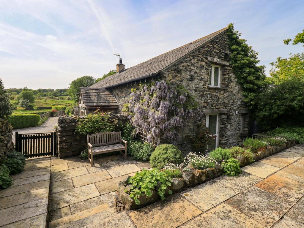 a stone house with a bench in the garden at Pheasant Cottage in Grange Over Sands