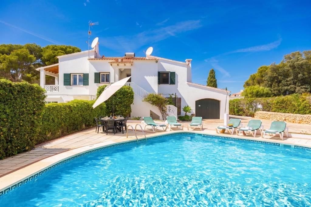 a villa with a swimming pool in front of a house at Villa Luisa in Cala Galdana