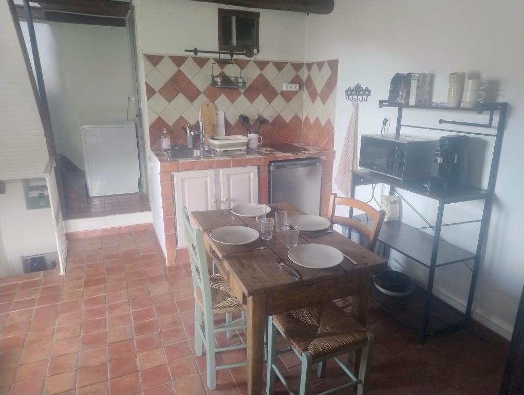 a kitchen with a wooden table with chairs and a microwave at Chez Eli in Luri