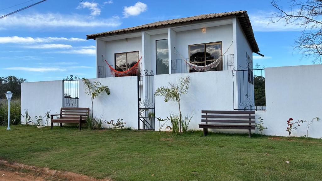 a white house with two benches in front of it at Casa Guimarães II in Chapada dos Guimarães
