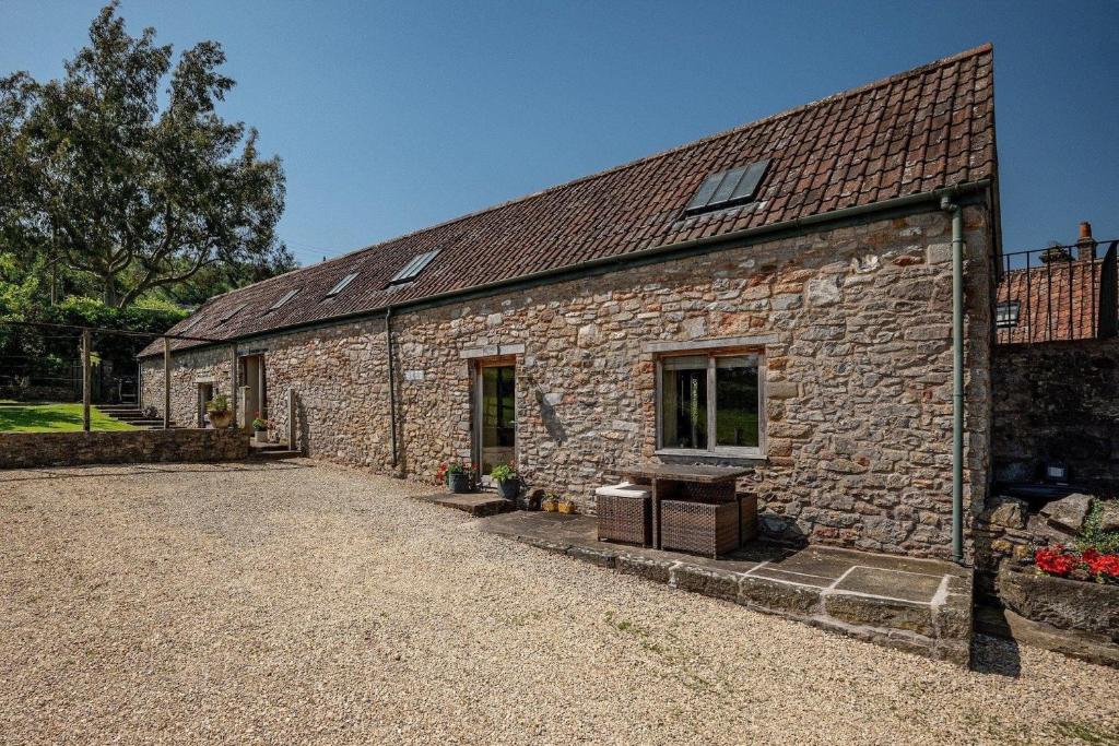 an old stone building with a window on it at Cosy Barn Conversion with Patio & Private Parking in Burrington