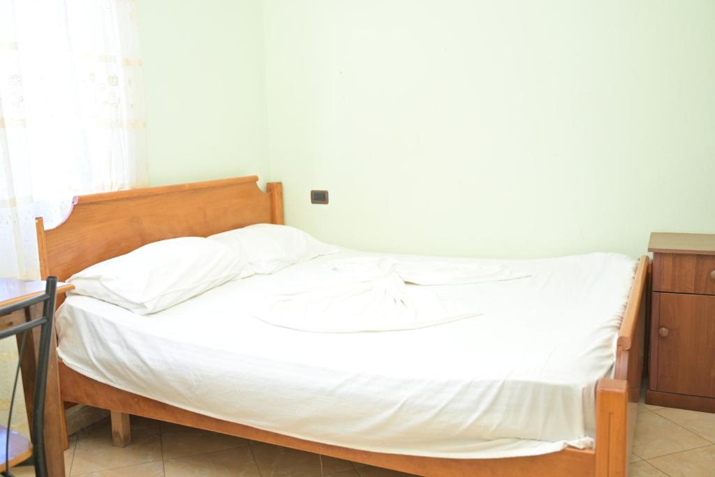 a bedroom with a bed with white sheets at Hotel Xhejsoni in Shëngjin