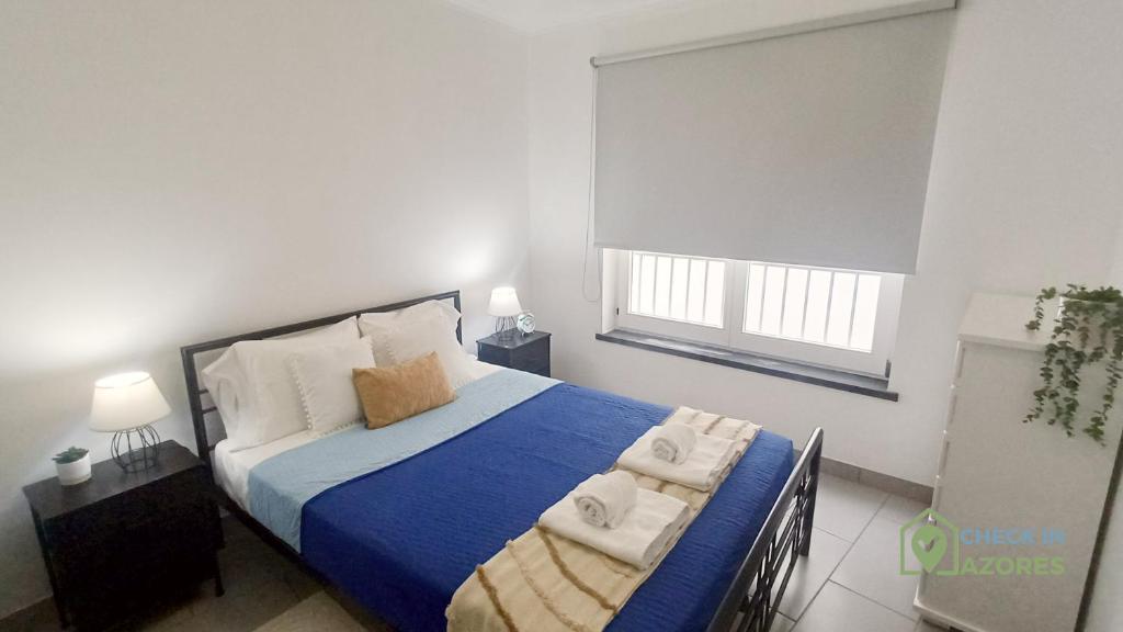 a bedroom with a bed with towels on it at Apartamento acolhedor com AC no centro de Angra in Angra do Heroísmo