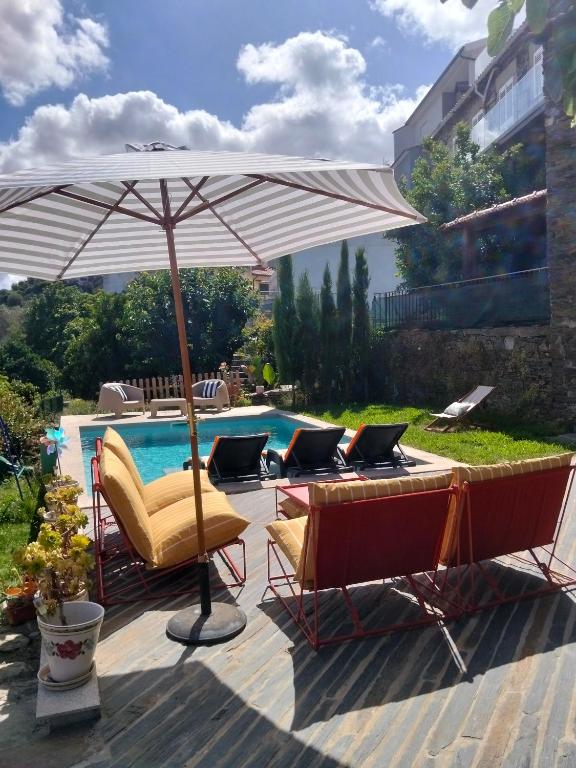 a patio with an umbrella and chairs and a pool at Refúgio no Douro in Nogueira