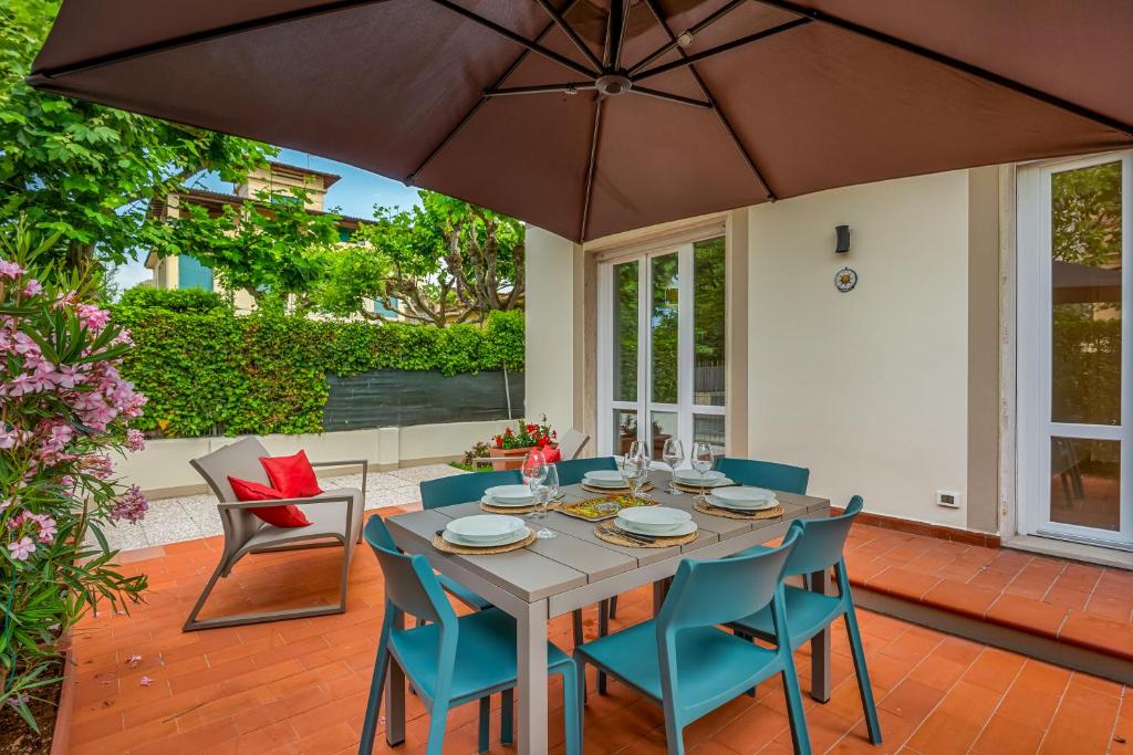 a table with chairs and an umbrella on a patio at GOLDEN LUXE - Sunset by the Sea in Lido di Camaiore