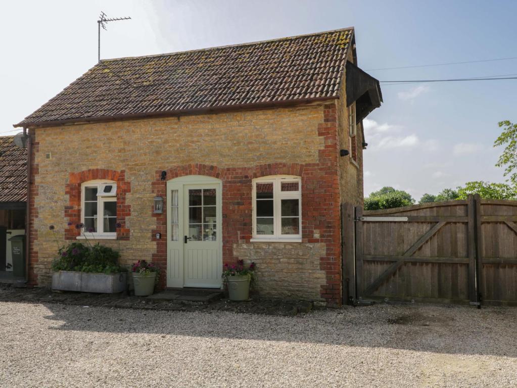 a small brick house with a wooden fence at Granary Cottage in Chippenham