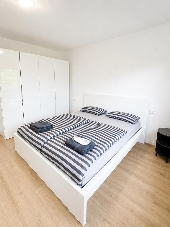 a white bed with black and white striped sheets at ILA vacation home Memmingen in Memmingen