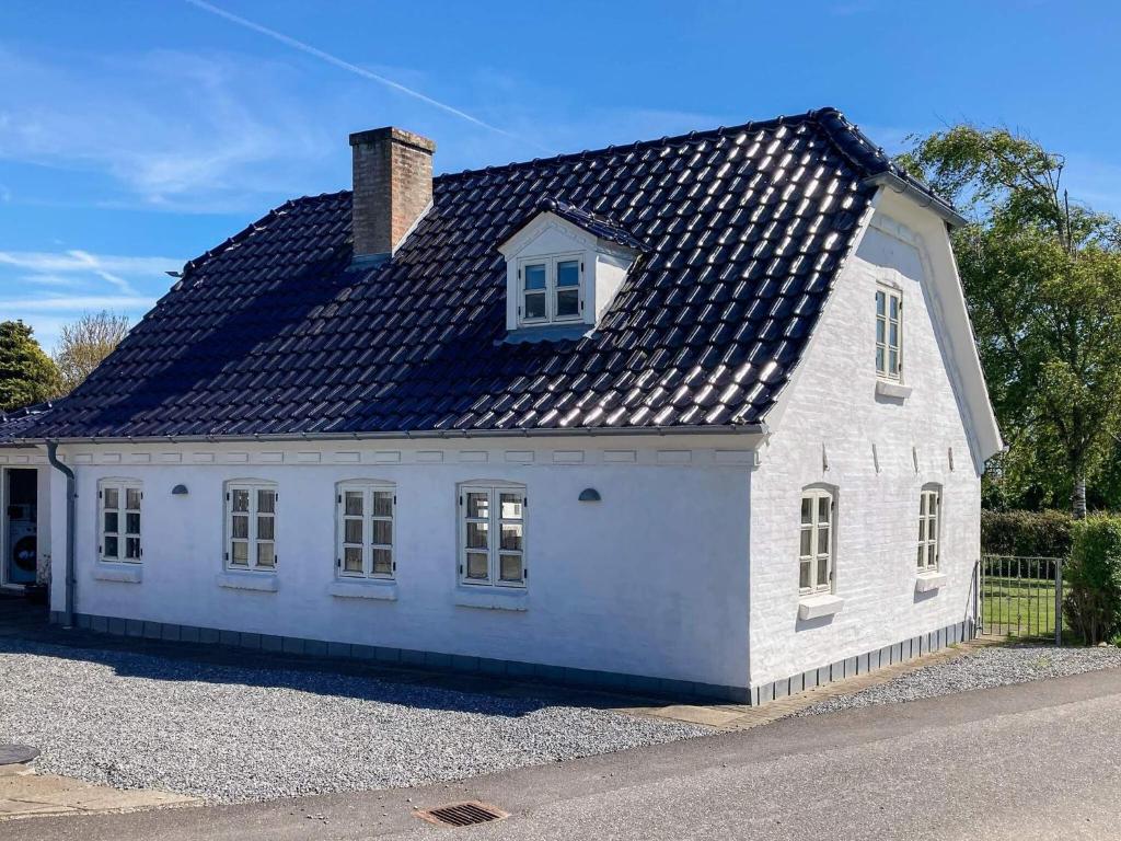 a white house with a black roof on a street at 5 person holiday home in Øster Assels-By Traum in Øster Assels