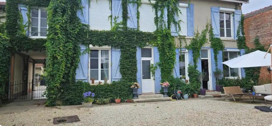 a house covered in green ivy with an umbrella at Chez Mary in Larzicourt