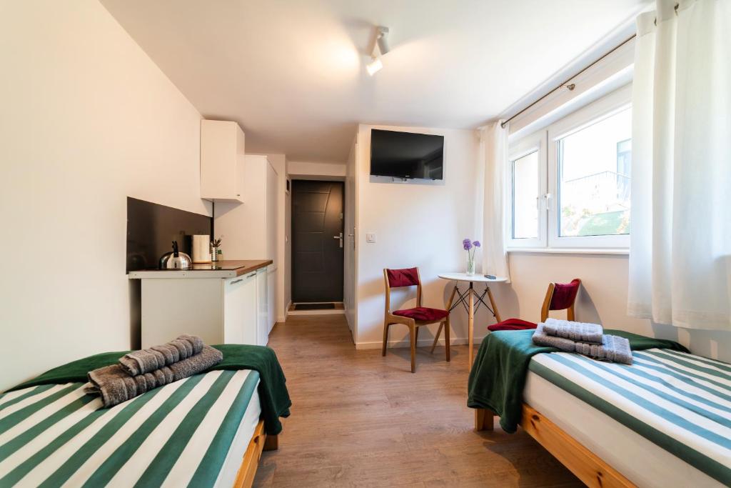 a room with two beds and a table and chairs at Pokój - Nad Zatoką in Jastarnia