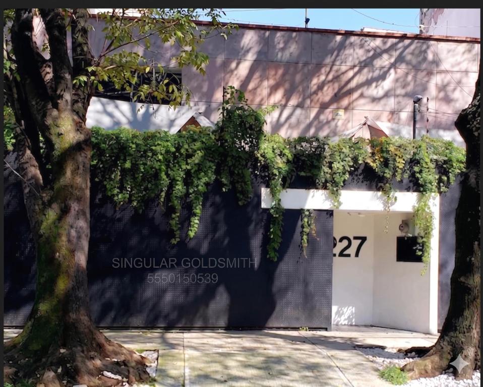 a building with a white garage with ivy on it at Singular Goldsmith in Mexico City