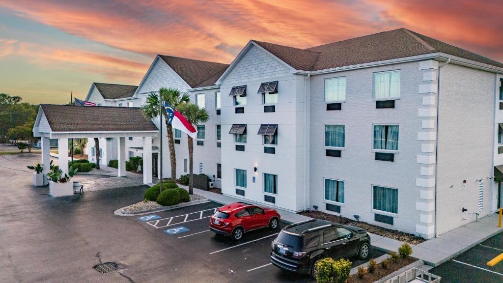 a hotel with a red car parked in a parking lot at The Windstar Hotel - Emerald Isle, Swansboro in Cedar Point