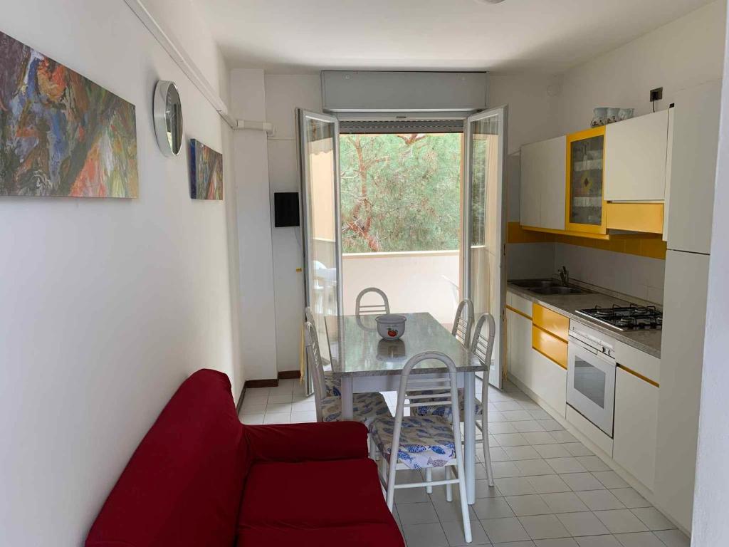 a small kitchen with a red couch and a table at Apartment with Pool in Rosolina Mare 57971 in Rosolina Mare