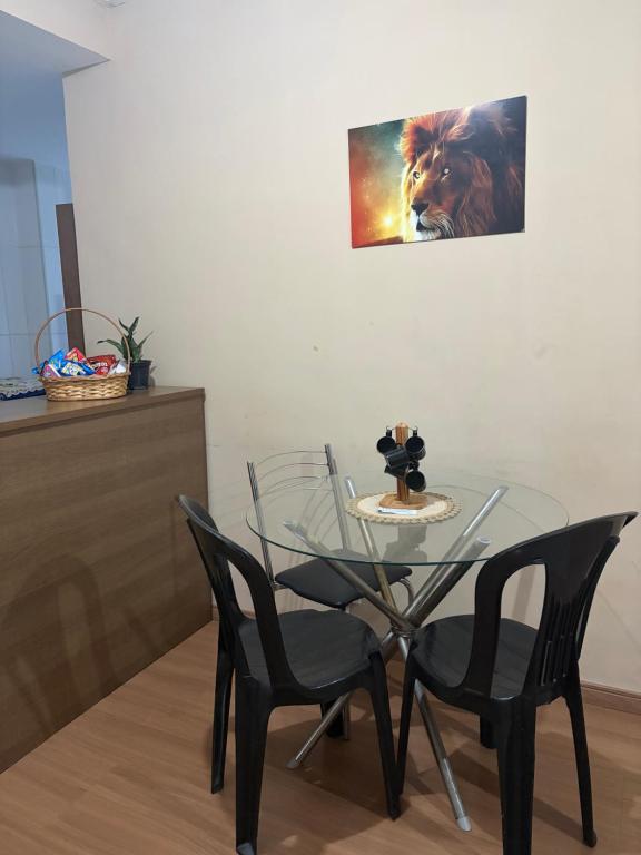 a glass table and chairs with a lion picture on the wall at Apto 2 qts em Xerém próximo ao CT do Fluminense in Duque de Caxias