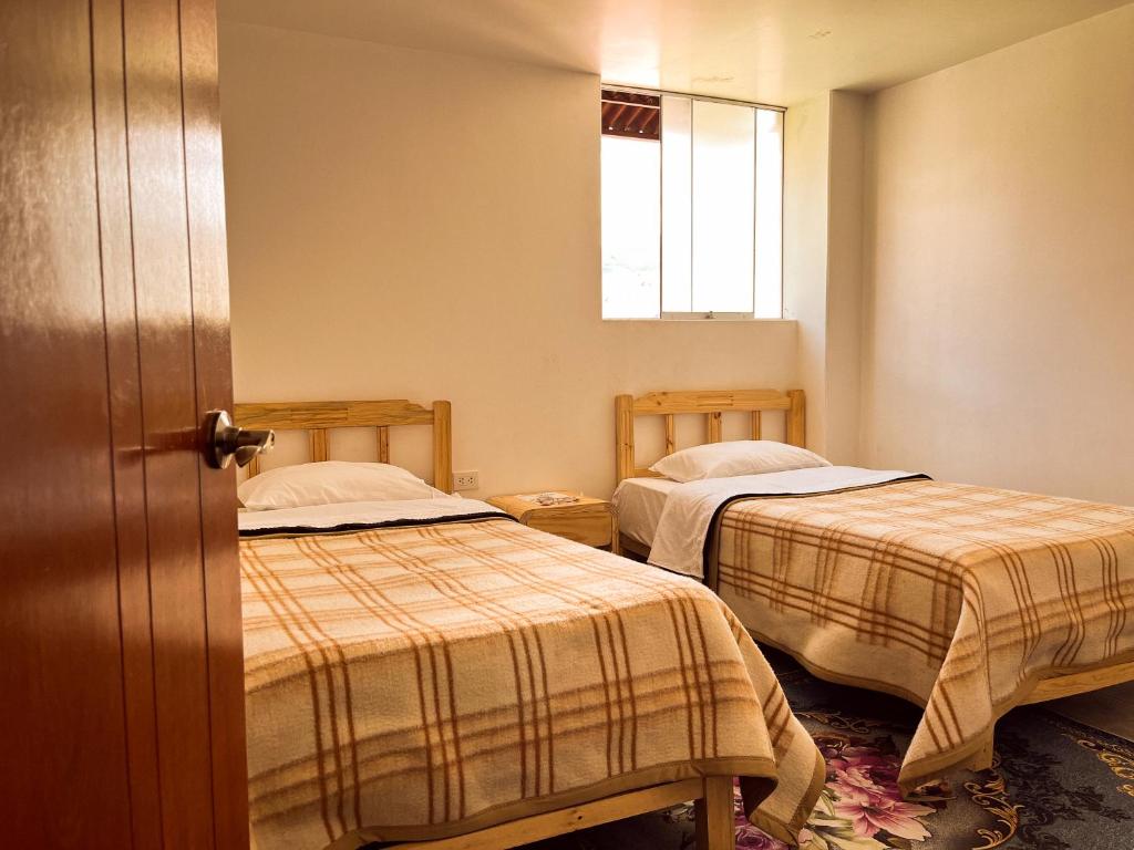a room with two beds and a window at Ayllu in Huaraz