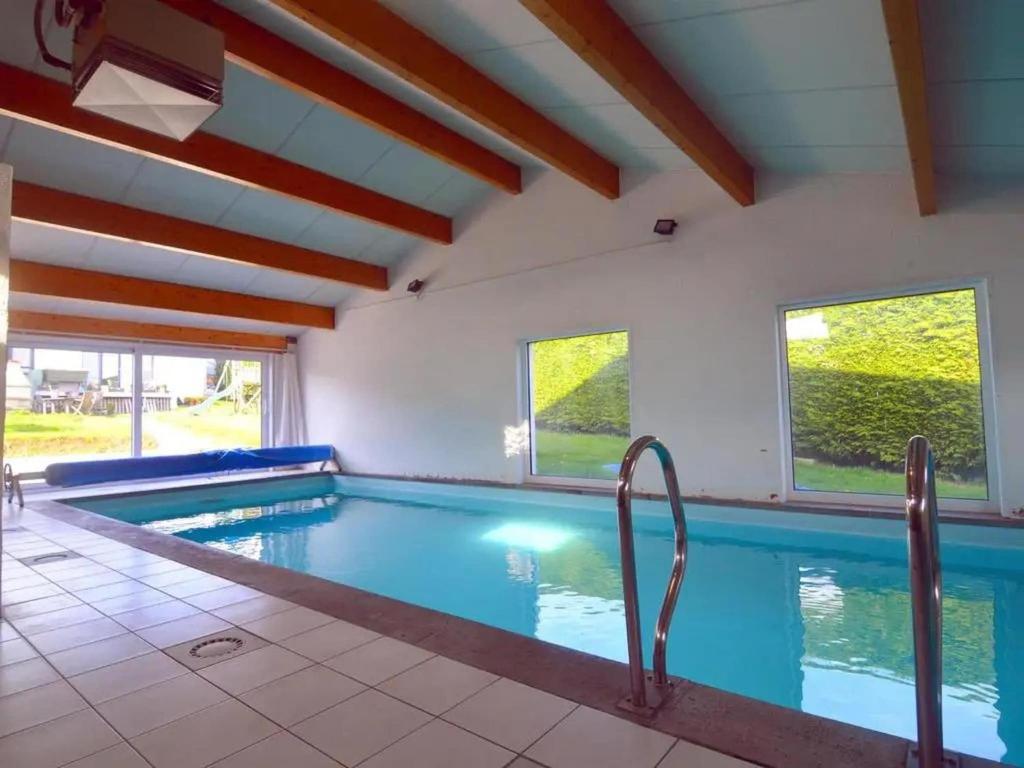a large swimming pool with blue water in a house at Sunny Cottage with Pool in Purnode