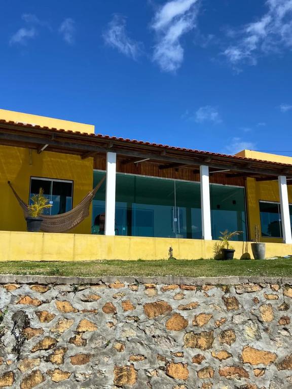 a yellow house with a hammock in front of it at Pousada Recanto do Oásis in Triunfo