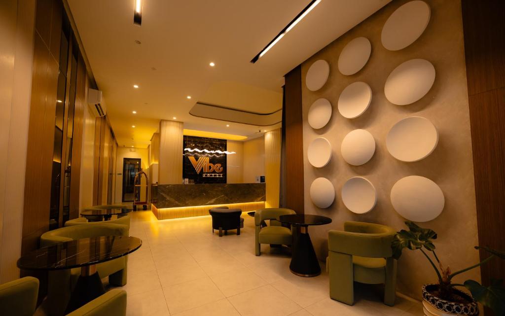 a lobby with a waiting area with tables and chairs at Vibe Hotel Alabang in Manila