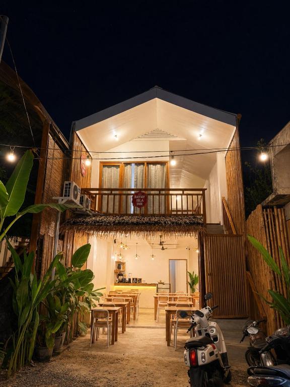 a restaurant with tables and a balcony at night at Bayay Isla Inn in General Luna