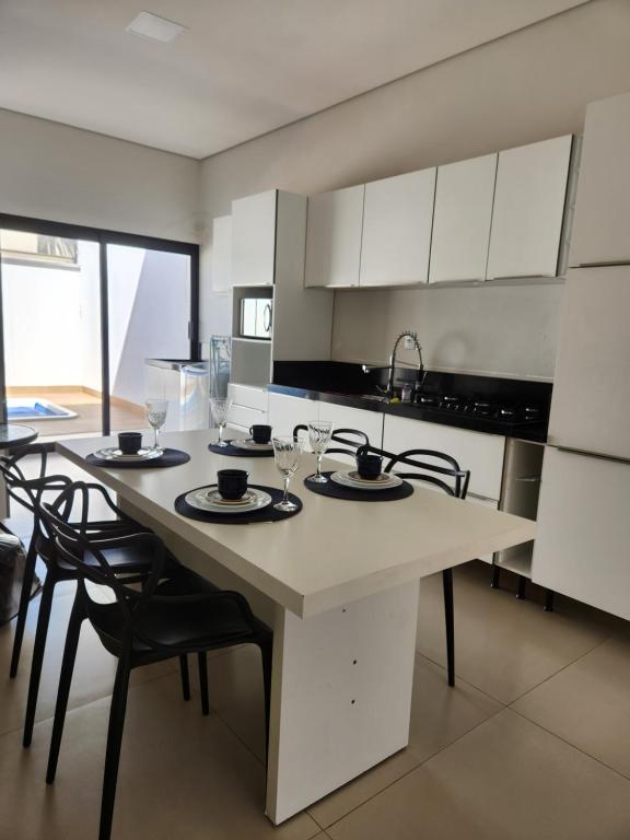 a kitchen with a table with chairs and glasses on it at Casa Completa e Funcional in Sinop