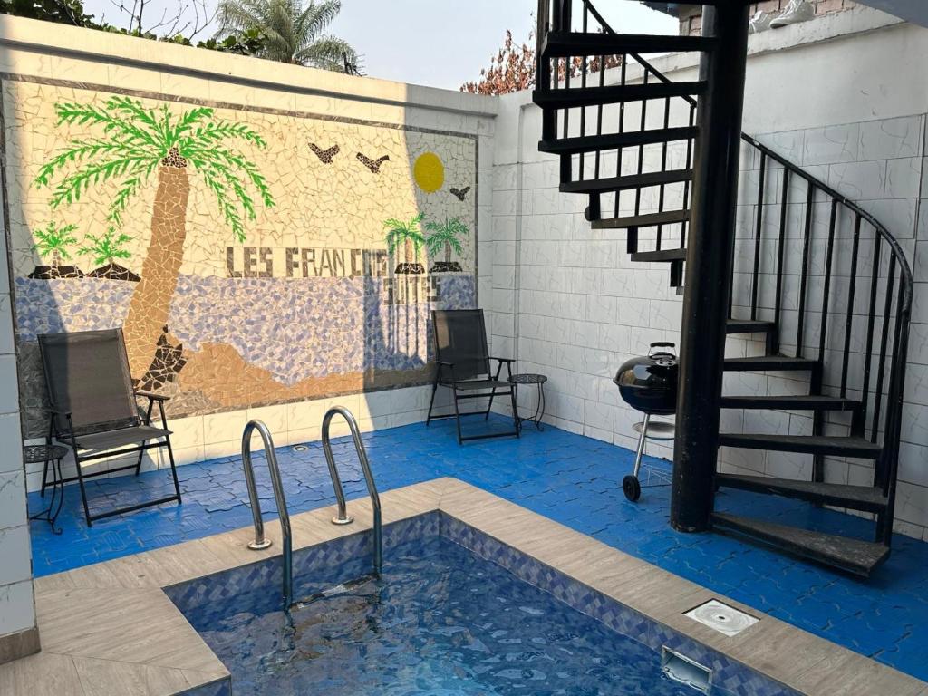 a pool with a staircase and a palm tree mural at L F Suites in Kinshasa